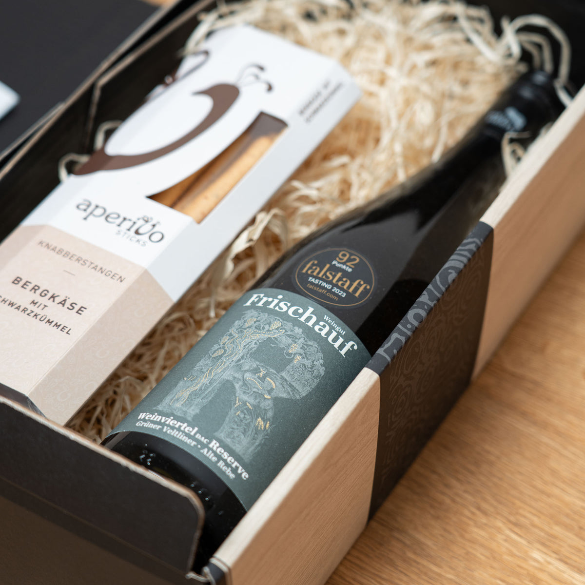 Kleiner Veltliner-Gruß mit Knabberei – geöffnetes Geschenkpaket